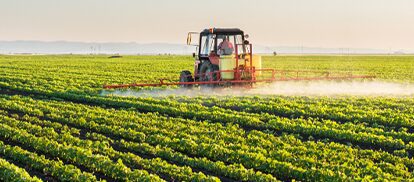 Farming equipment spraying in green field