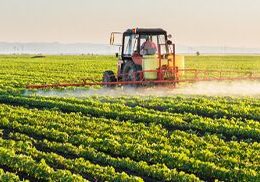 Farming equipment spraying in green field